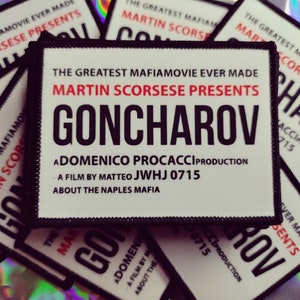 Könnte beinhalten: Eine Ansammlung weißer, rechteckiger Aufnäher mit schwarzen Rändern. Die Aufnäher zeigen den Text "GONCHAROV" in großen schwarzen Buchstaben, mit "MARTIN SCORSESE PRESENTS" in Rot. Zusätzlicher Text lautet "THE GREATEST MAFIAMOVIE EVER MADE" und Film Credits.