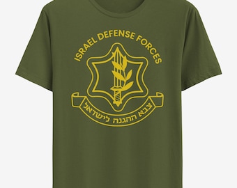 May include: A green t-shirt with a yellow graphic of the Israel Defense Forces logo. The logo features a Star of David with a sword and olive branch inside. The text "ISRAEL DEFENSE FORCES" is written in a circle around the star. The text "צבא ההגנה לישראל" is written in Hebrew on a banner below the star.