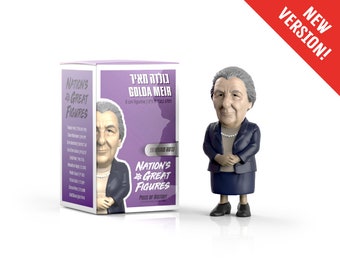May include: A purple box with a picture of Golda Meir on the front. The box says "Nation's Great Figures" and "Golda Meir". There is a small figurine of Golda Meir standing in front of the box. The figurine is 8 cm tall.