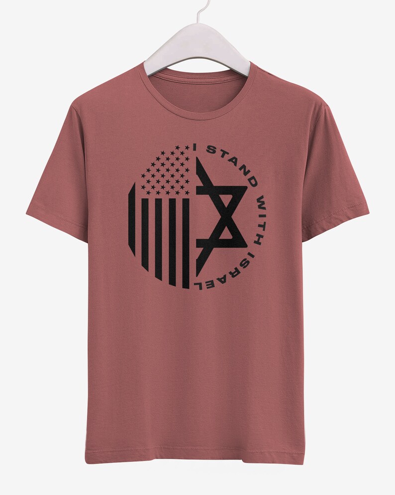 May include: A dusty rose t-shirt with a black graphic. The graphic features a circular design with the American flag on the left and a Star of David on the right, with the text "I STAND WITH ISRAEL" around the circle.