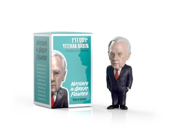 May include: A 8 cm figurine of Yitzhak Rabin, the former Prime Minister of Israel, in a dark suit and red tie. The figurine is part of the Nation's Great Figures collection, a series of collectible figurines of historical figures. The box for the figurine is teal blue with white text and a star of David.