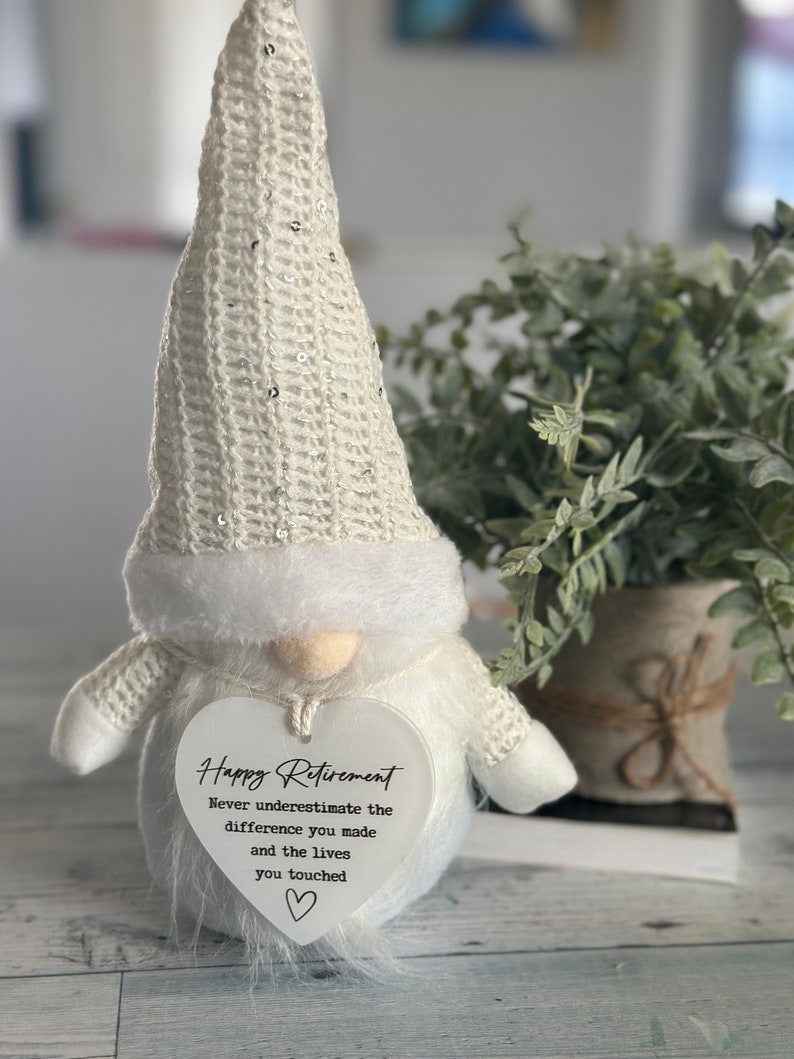 May include: White gnome figurine with a heart-shaped sign that reads "Happy Retirement Never underestimate the difference you made and the lives you touched".