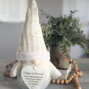 May include: White gnome figurine with a heart-shaped sign that reads "Happy Retirement Never underestimate the difference you made and the lives you touched".
