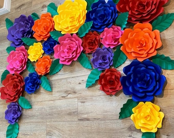 Könnte beinhalten: Eine bunte Papierblumen-Girlande mit großen, geschichteten Blüten in Rot-, Orange-, Gelb-, Grün-, Blau-, Lila- und Rosatönen. Die Blüten sind in einem kaskadierenden Muster angeordnet und schaffen einen festlichen und verspielten Hintergrund.