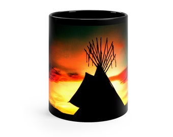 May include: A black coffee mug with a colorful sunset scene featuring a silhouette of a teepee with wooden poles.