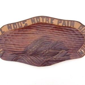 May include: A wooden serving tray with a carved design of wheat stalks. The tray is brown and has the words "Don't you no the pain of waiting" carved around the edge.