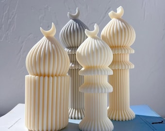 Puede incluir: Conjunto de cuatro velas decorativas con forma de mezquitas, con dos velas blancas y dos grises. Las velas tienen una textura acanalada y una luna creciente en la parte superior.
