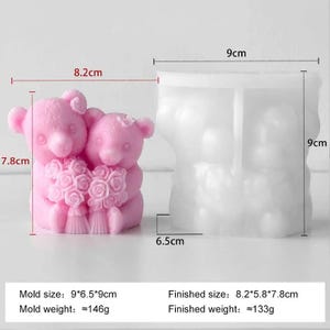 May include: A pink silicone mould and a finished pink candle shaped like two teddy bears holding a bouquet of flowers. The mould measures 9 cm x 6.5 cm x 9 cm. The finished candle measures 8.2 cm x 5.8 cm x 7.8 cm.