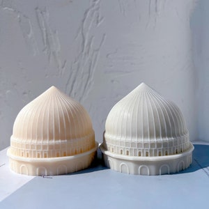 May include: Two white ceramic dome-shaped decorative objects with intricate details. The dome on the left is a lighter shade of white.