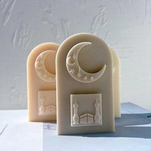 Può includere: Due portacandele decorativi bianchi con un design a mezzaluna e stelle. La parte inferiore di ogni portacandele presenta una moschea con una cupola e due minareti.