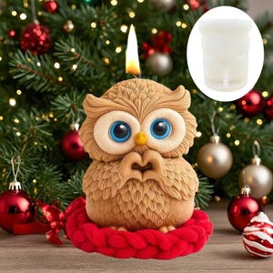 Pode incluir: Uma vela em forma de coruja marrom com grandes olhos azuis e um bico amarelo, sobre uma base vermelha tricotada. A vela tem um pavio aceso. Fundo de árvore de Natal com enfeites.