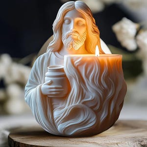 Könnte beinhalten: Ein weißer religiöser Kerzenhalter in Form einer Statue von Jesus mit langem Haar und Bart, der ein Gefäß hält. Die Kerze ist angezündet, mit einem warmen Schein, der von der Flamme und der Kerze ausgeht. Der Kerzenhalter steht auf einer Holzoberfläche.