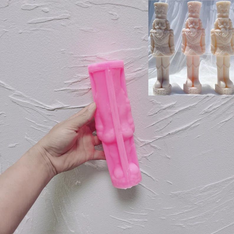 May include: Pink silicone mold for making a nutcracker candle. The mold is shaped like a standing nutcracker with a hat and a sword.