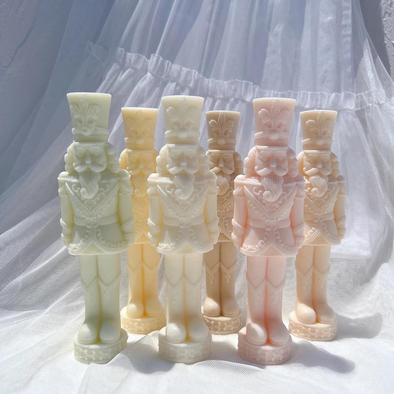 May include: Six white and pink nutcracker candle holders in various sizes. The nutcrackers are decorated with intricate details and have a vintage look.