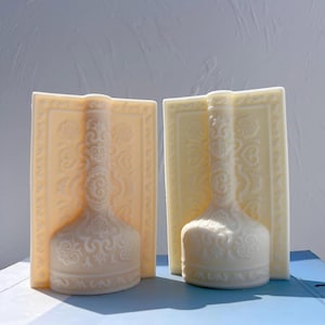 Puede incluir: Dos tapones de botella de cerámica blanca con intrincados diseños florales. Los tapones tienen forma de botella y presentan un diseño en relieve en la parte delantera y trasera.