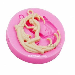 May include: A pink silicone mold featuring a cream-colored design of a woman embracing a crescent moon. The mold has a circular shape with the text "TUTULE" and "MsDIYSupplies.com" printed on it.