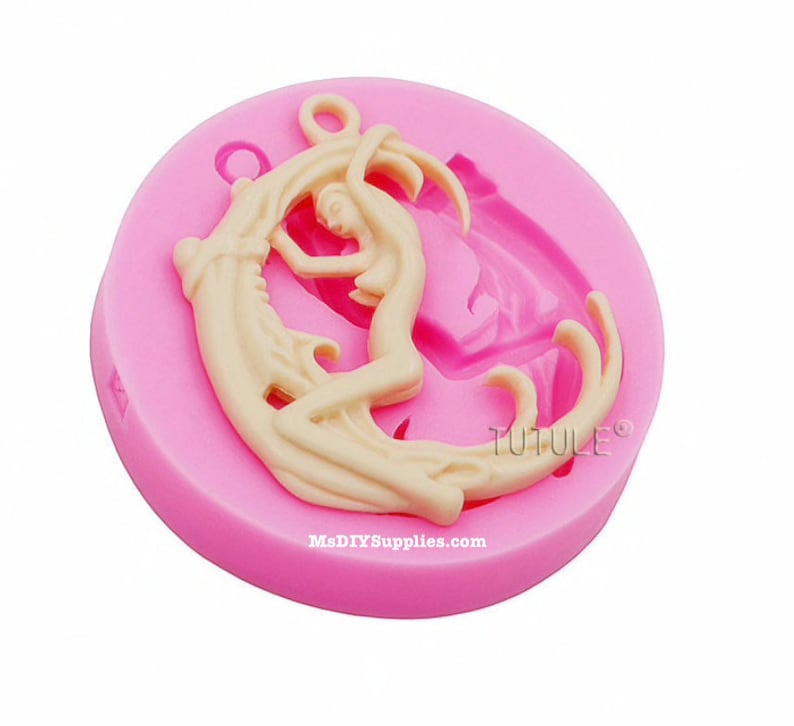 May include: A pink silicone mold featuring a cream-colored design of a woman embracing a crescent moon. The mold has a circular shape with the text "TUTULE" and "MsDIYSupplies.com" printed on it.