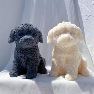 May include: Two small dog figurines, one black and one white, are sitting on a white surface. The figurines are made of a soft, furry material and have realistic features.