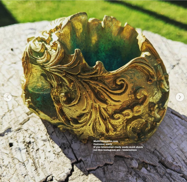 May include: A gold-colored, ornate resin container with a green interior. The container features detailed, swirling patterns and is set on a weathered wooden surface. The text "MaDIYSupplies.com" is visible.
