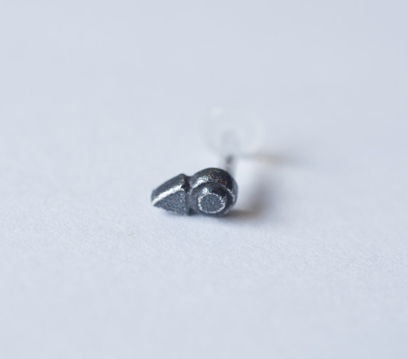 Puede incluir: Un peque&ntilde;o aro para la nariz de plata con un dise&ntilde;o geom&eacute;trico simple. El aro est&aacute; hecho de metal y tiene un acabado liso y pulido.