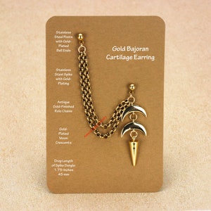 Peut inclure: Boucle d'oreille cartilage Gold Bajoran dor&eacute;e avec cha&icirc;ne, croissants de lune et pendentif en forme de pointe. L'accessoire est pr&eacute;sent&eacute; sur une carte marron. La longueur de la pointe est de 4,4 cm.