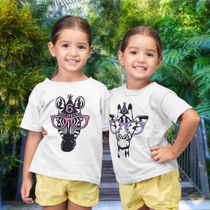 May include: Two young girls wearing white t-shirts with animal graphics. One shirt features a zebra wearing pink glasses and a party hat with the number 6. The other shirt has a giraffe with purple glasses and a party hat with the number 6.