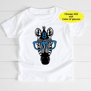 May include: White t-shirt featuring a black and white zebra head wearing blue glasses and a party hat with the number 8. The text "Change AGE and Color of glasses" is in a yellow oval.