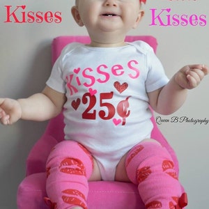 May include: A baby in a white onesie with "Kisses" and "25&cent;" graphics, pink leg warmers with red lip prints, and a pink floral headband. The baby sits on a pink chair. The image has text that says "Kisses".