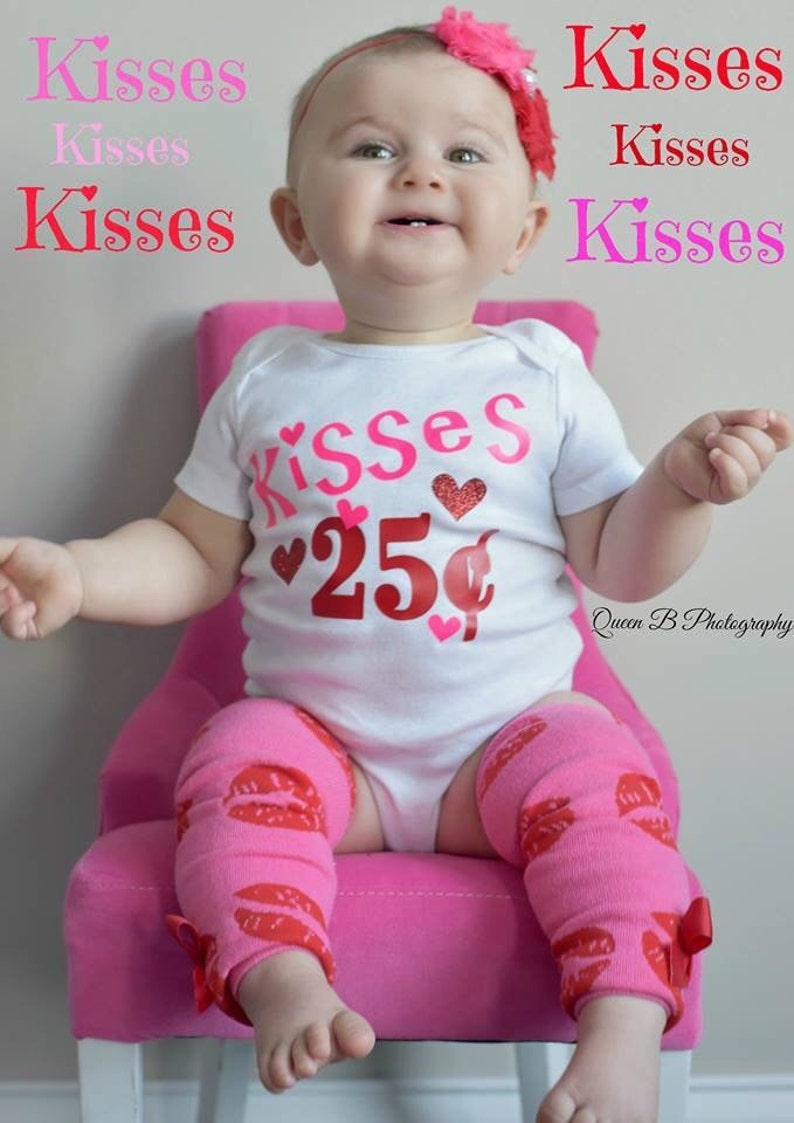 May include: A baby in a white onesie with "Kisses" and "25&cent;" graphics, pink leg warmers with red lip prints, and a pink floral headband. The baby sits on a pink chair. The image has text that says "Kisses".