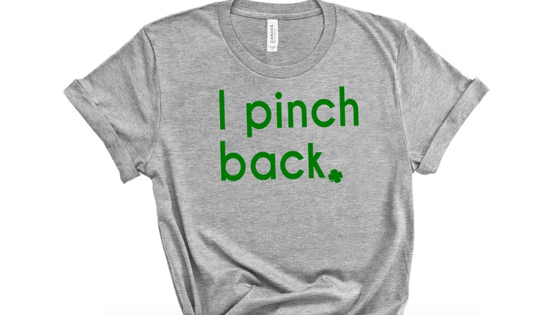 May include: A heather gray t-shirt with the text "I pinch back" in green, along with a green shamrock. The shirt has rolled-up sleeves and a crew neck. The shirt is made of a soft material.