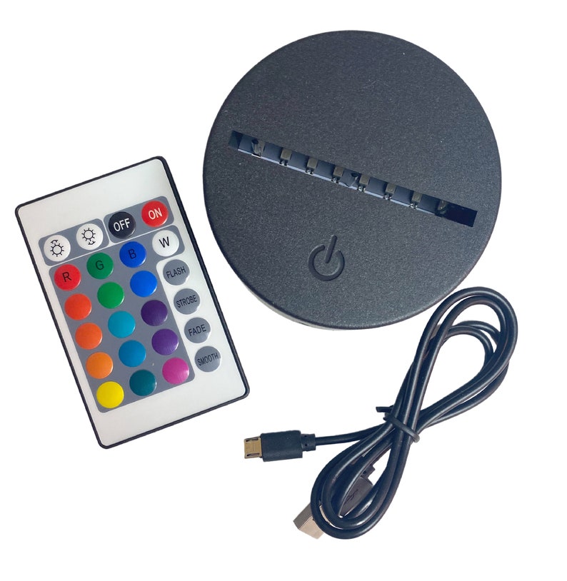Puede incluir: Una base LED negra con un bot&oacute;n de encendido, un mando a distancia con opciones de color y un cable USB. El mando tiene botones para la selecci&oacute;n de color, brillo y efectos especiales como estrobosc&oacute;pico y fundido. La base es redonda.