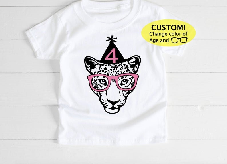 May include: White t-shirt featuring a leopard face wearing pink glasses and a party hat with the number 4. The text "CUSTOM! Change color of Age and" is in a yellow oval on the right side of the shirt.