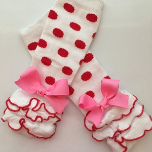 K&ouml;nnte beinhalten: Wei&szlig;e Beinw&auml;rmer mit roten Tupfen und rosa Schleifen. Die Beinw&auml;rmer haben eine R&uuml;schenborte mit roter Kante.