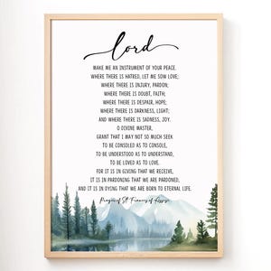 May include: Framed print featuring the text "lord" in elegant script, followed by a prayer. The artwork includes a watercolor landscape of mountains, trees, and a lake at the bottom. The frame is a light wood color.