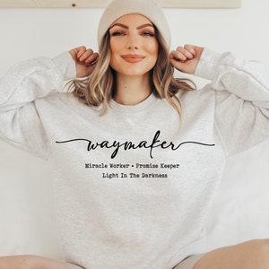 May include: A gray sweatshirt with the text "waymaker" in cursive script. Below the text, it reads "Miracle Worker - Promise Keeper Light In The Darkness".