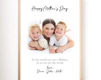 May include: A framed print with a light wood frame. The print features a photo of a woman and two children smiling. The text "Happy Mother's Day" is at the top, with a message and names below.