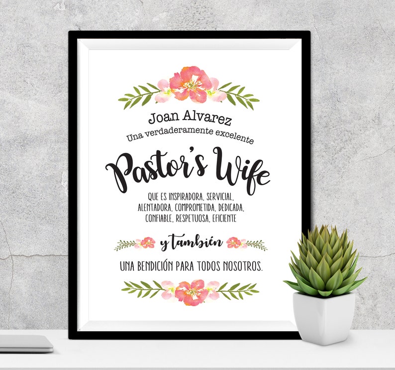 May include: A framed print with a floral design and the text "Joan Alvarez Una verdaderamente excelente Pastor's Wife QUE ES INSPIRADORA, SERVICIAL. ALENTADORA, COMPROMETIDA, DEDICADA, CONFIABLE, RESPETUOSA, EFICIENTE y tambi&eacute;n UNA BENDICI&Oacute;N PARA TODOS NOSOTROS."