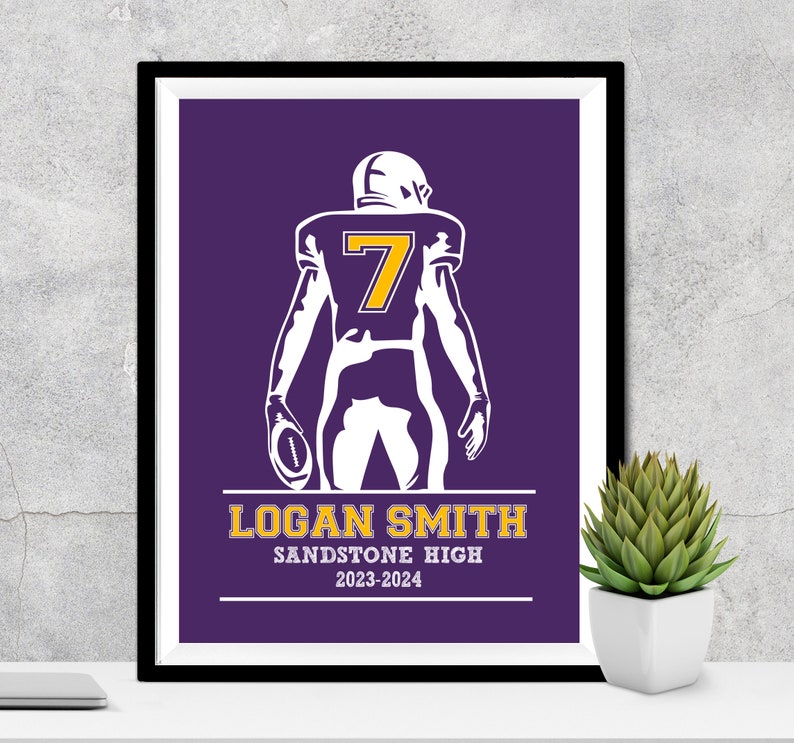 Puede incluir: Impresi&oacute;n enmarcada de un jugador de f&uacute;tbol americano con uniforme morado y el n&uacute;mero 7 en dorado. El jugador sostiene un bal&oacute;n de f&uacute;tbol. La impresi&oacute;n incluye el nombre "LOGAN SMITH", "SANDSTONE HIGH" y el rango de a&ntilde;os "2023-2024".