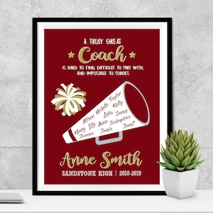 May include: A red and white framed print with a gold glitter design that says "A Truly Great Coach is hard to find, difficult to part with, and impossible to forget." The print also features a white megaphone with names written on it and a white pom-pom. The print also says "Anne Smith Sandstone High | 2018-2019".
