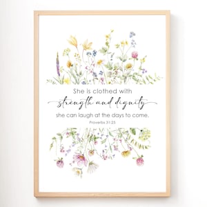 Könnte beinhalten: Ein gerahmter Kunstdruck mit einem Aquarell-Blumenmuster in Gelb, Rosa und Lila. Der Text lautet: "Sie ist bekleidet mit Stärke und Würde, sie kann über die Zukunft lachen. Sprüche 31,25."