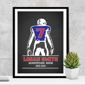 Puede incluir: Impresi&oacute;n enmarcada de un jugador de f&uacute;tbol americano con camiseta azul y el n&uacute;mero 7. El jugador sostiene un bal&oacute;n. Debajo, el texto dice "LOGAN SMITH SANDSTONE HIGH 2023-2024". La impresi&oacute;n est&aacute; en un marco negro.