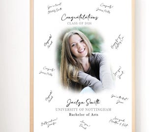 May include: A framed graduation print featuring a photo of a woman, surrounded by handwritten congratulatory messages. The print includes the text "Congratulations Class of 2026," the graduate's name, university, and degree. The frame is a light wood color.