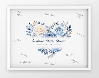 May include: A white framed print featuring a central floral arrangement of cream and blue roses with green leaves. The text reads Welcome Baby Jamie and 05.21.2027. The surrounding white space contains various handwritten signatures and messages.