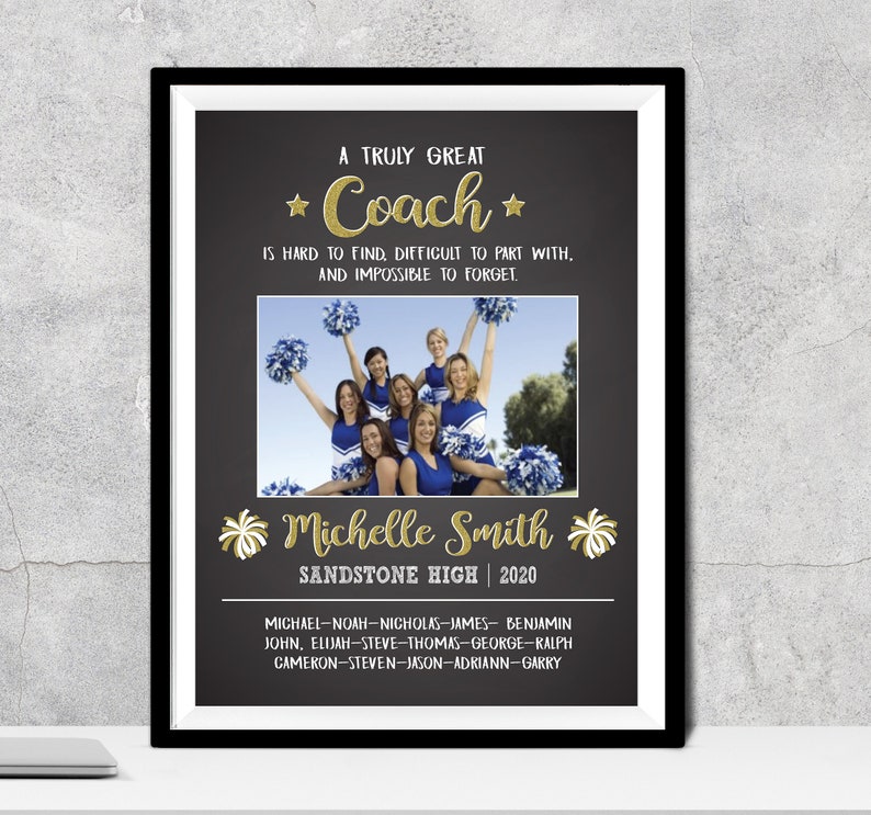 May include: Framed print with a black border. The print features a photo of a cheerleading squad in blue and white uniforms. Text in gold glitter reads "A Truly Great Coach" and "Michelle Smith, Sandstone High 2020."