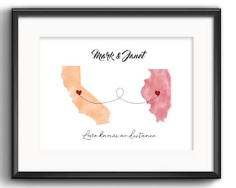 May include: Framed art print featuring watercolor maps of California and Illinois, connected by a dotted line with hearts. The names "Mark & Janet" are above the maps, and the phrase "Love knows no distance" is below.