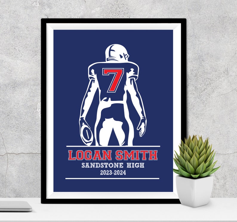 Puede incluir: Impresi&oacute;n enmarcada de un jugador de f&uacute;tbol americano con uniforme blanco y el n&uacute;mero 7 en rojo. El jugador sostiene un bal&oacute;n sobre un fondo azul. La impresi&oacute;n incluye el nombre "LOGAN SMITH" y "SANDSTONE HIGH 2023-2024".