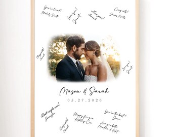May include: A framed wedding photo featuring a couple with signatures and well wishes. The photo includes the names "Mason & Sarah" and the date "05.27.2026". The frame is light-colored, and the background is white.