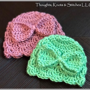 May include: Two crocheted hats with bows. One hat is pink and the other is green.