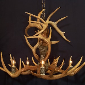 May include: A chandelier made from antlers with six light bulbs. The antlers are arranged in a circular pattern with the bulbs in the center. The chandelier is hanging from a chain.