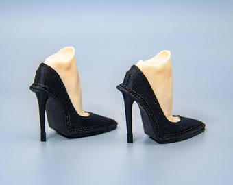May include: A pair of black high-heeled shoes with pointed toes. The shoes have a delicate strap detail around the ankle.